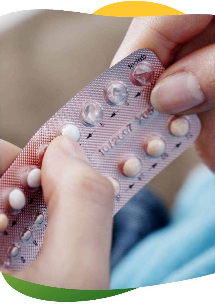 Woman’s hands pressing the birth control pill out of the package